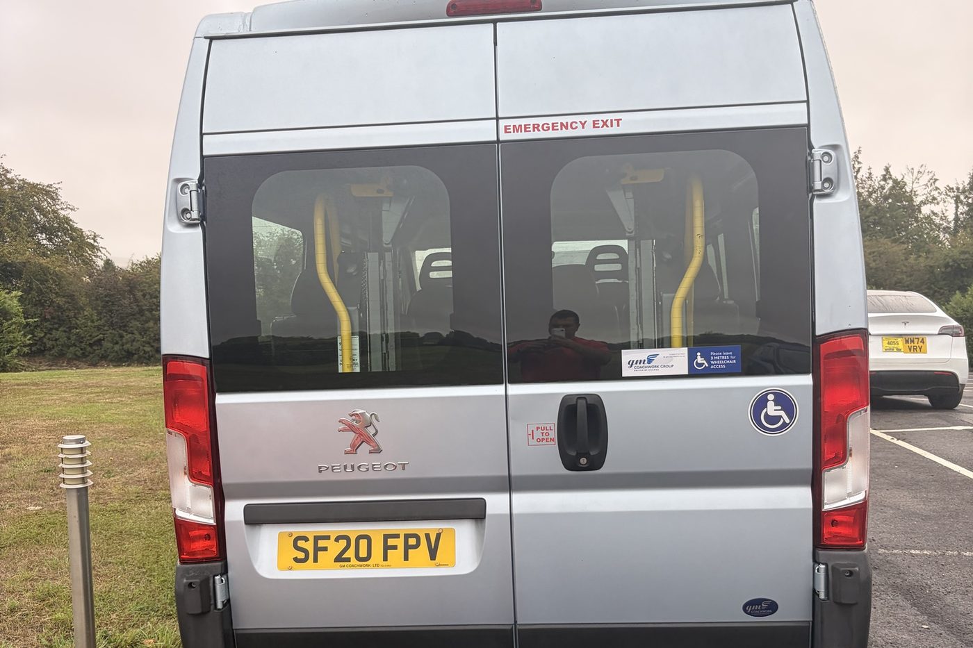 Rear doors of a silver accessible minibus, with yellow grab rails inside, a wheelchair symbol and a sign asking drivers to leave 3 metres for wheelchair access