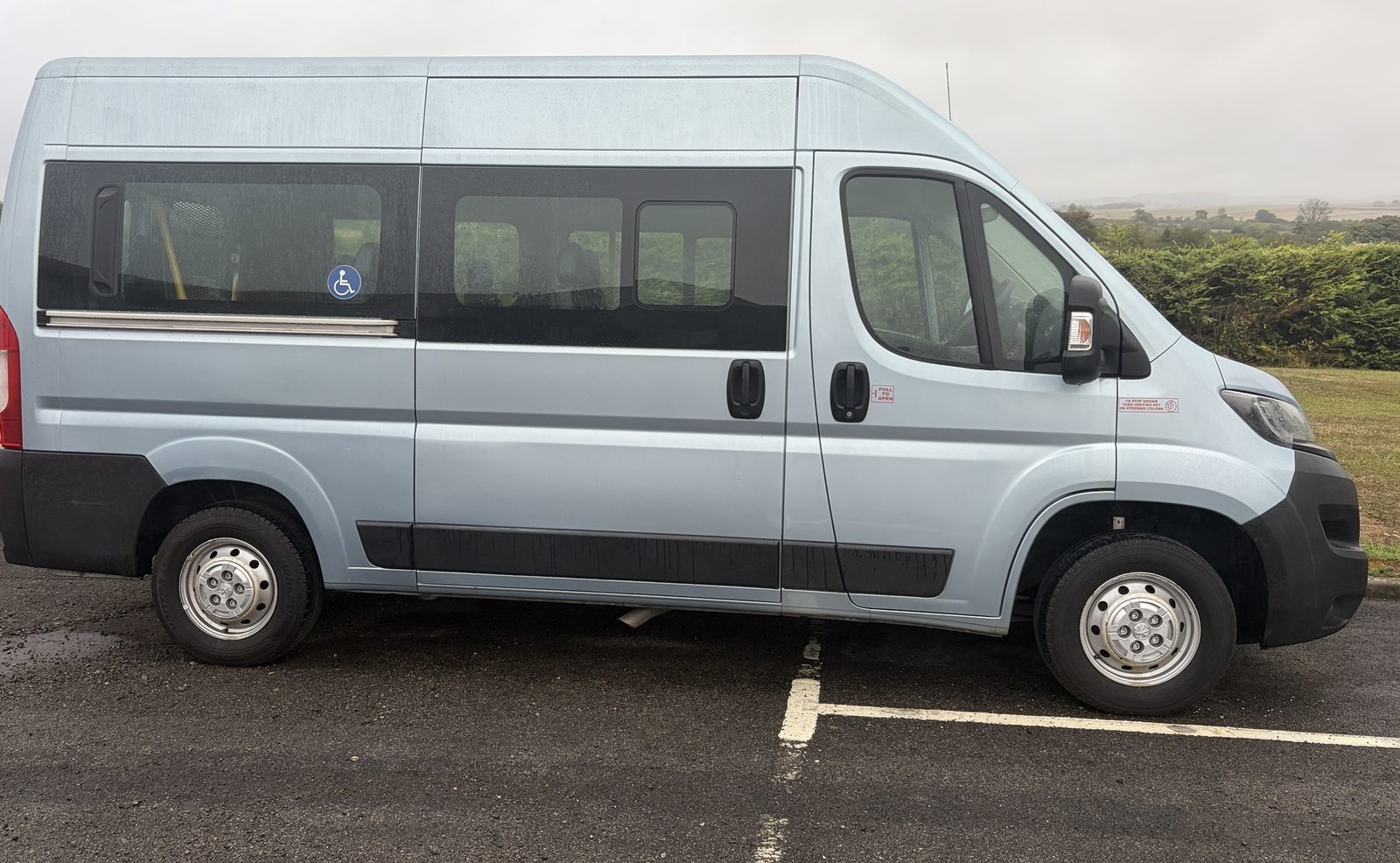 Silver high-roof minibus with a wheelchair access sign in the side window