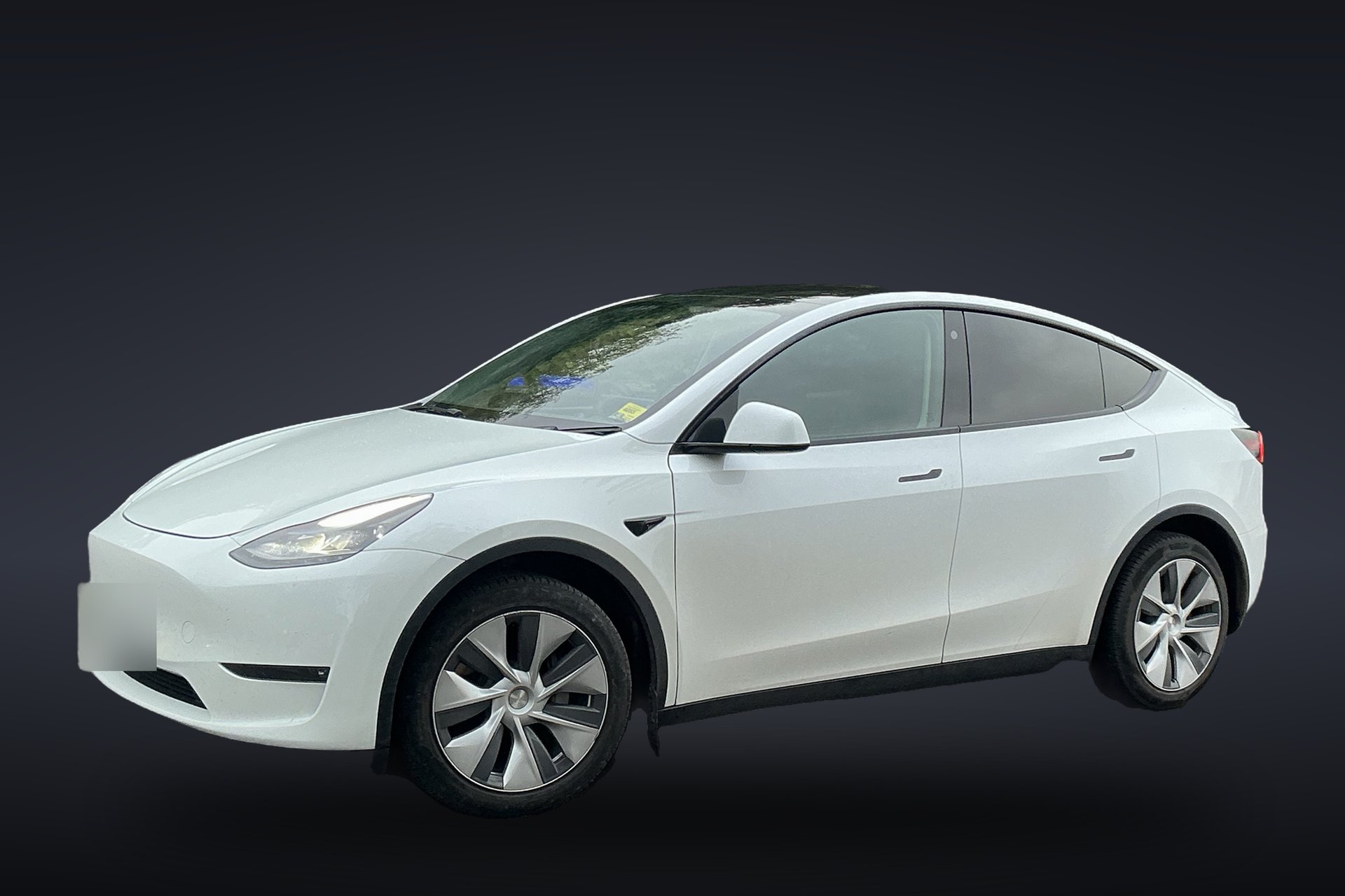White Tesla Model Y seen from the front three-quarter angle, on a dark grey studio background